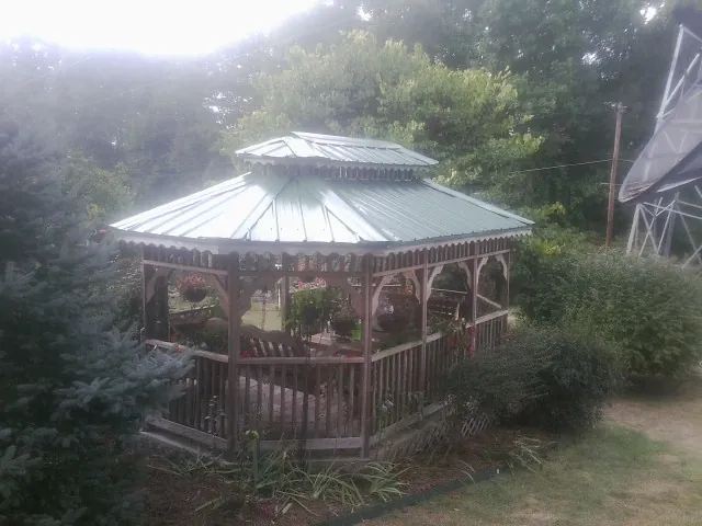 Green metal roof on a backyard gazebo surrounded by garden beds in Shelter Island