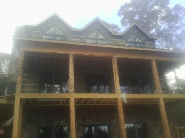 Dormers and porch framing on a large log home under construction — Roof Coating work by our crew in Shelter Island