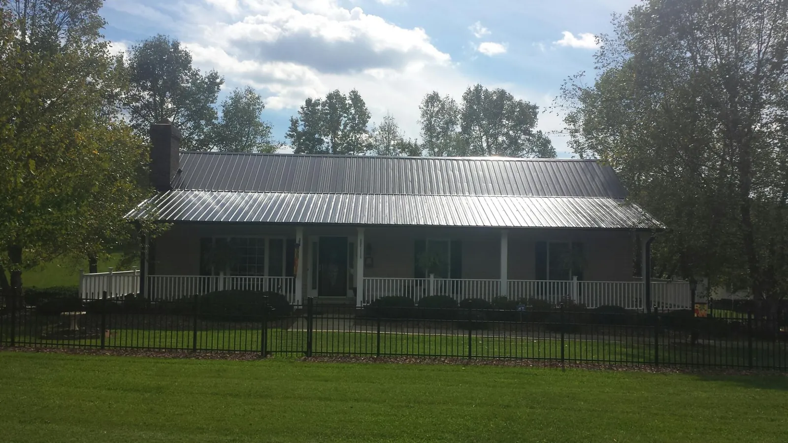 Gray metal roof on a brick ranch with a full width front porch — Gutter Guard Installation work by our crew in Shelter Island