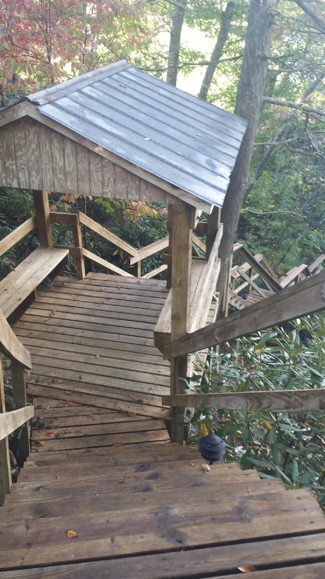 Metal roofed shelter over wooden steps on a wooded walkway — Skylight Repair & Installation work by our crew in Shelter Island