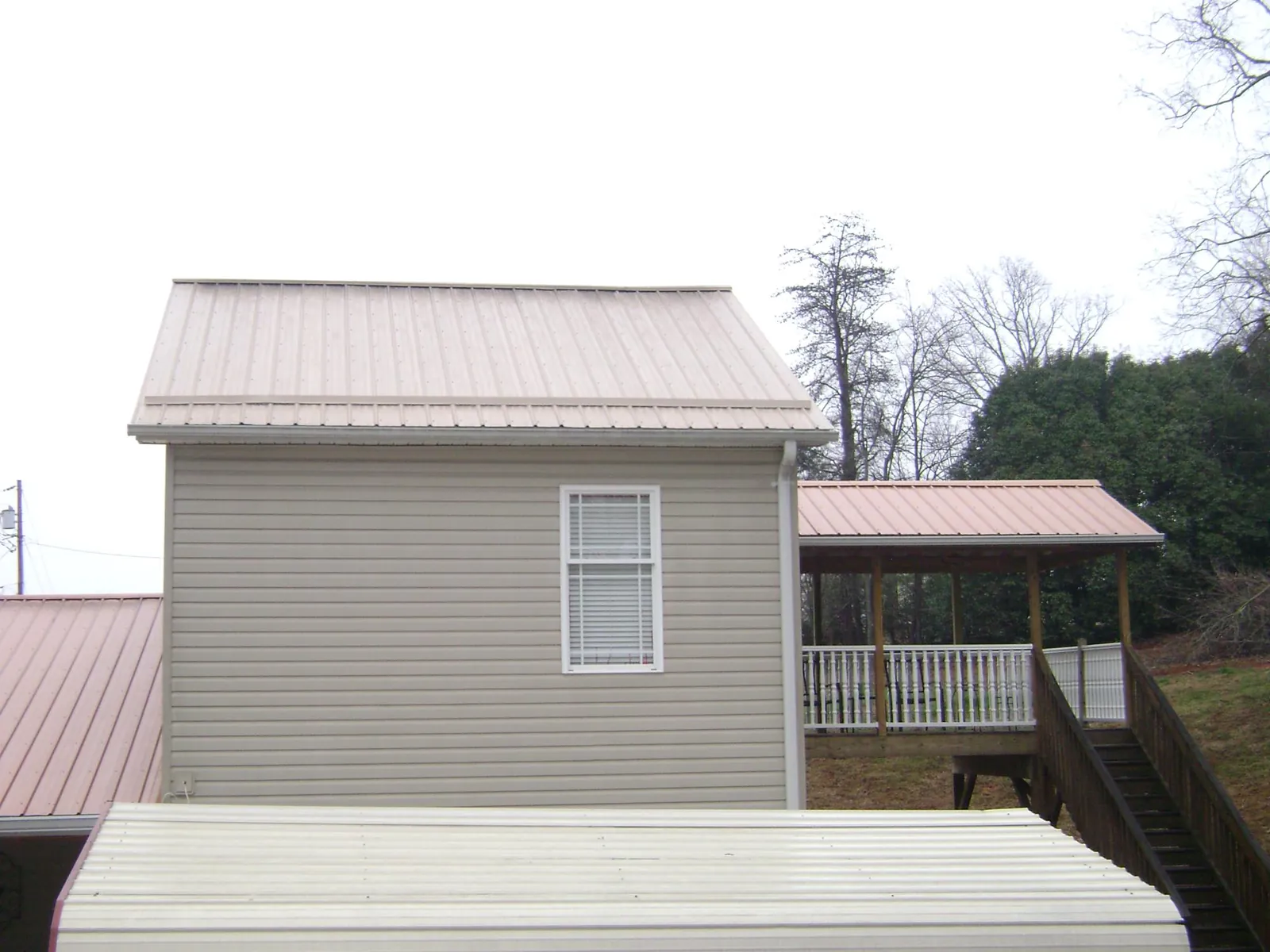 Tan metal roofs on a two story addition and attached porch, from a Roof Replacement job in Shelter Island