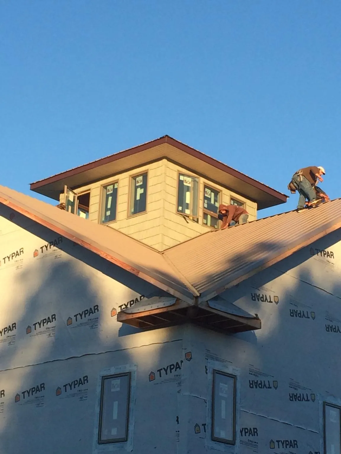 Roofers working around a rooftop cupola on a new metal roof at sunset — Roof Waterproofing in Shelter Island by Roofing Brothers